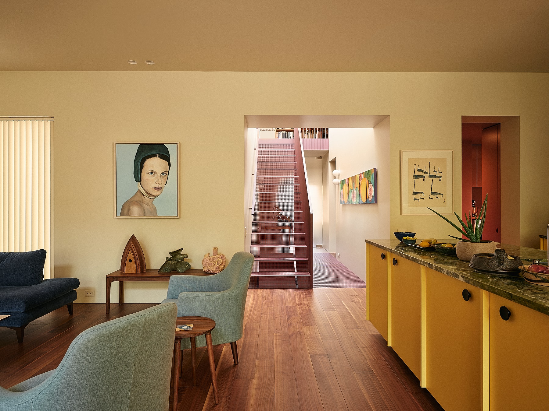 Intérieur de la Maison King-Edward par La Shed Architecture avec escalier rouge central et cuisine colorée.