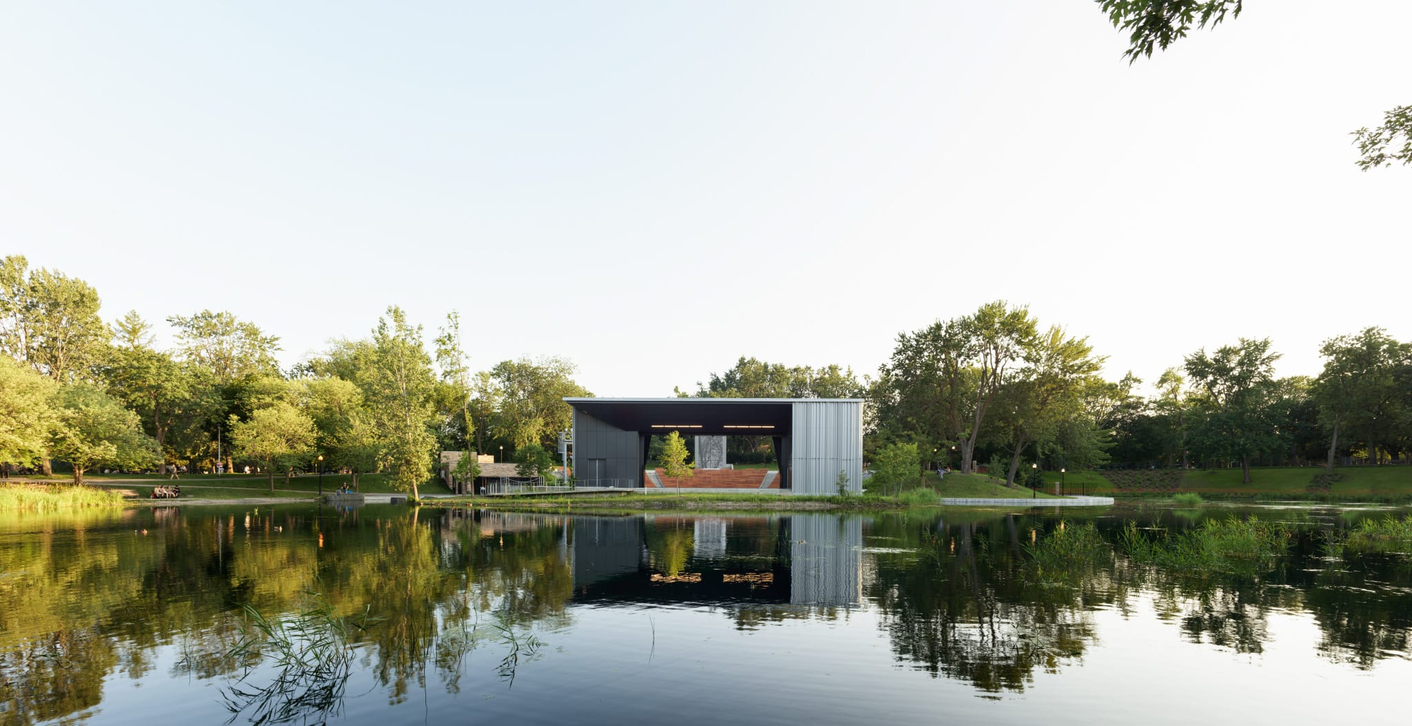 Le Théâtre de Verdure conçu par Lemay au parc La Fontaine à Montréal, vu depuis le lac avec reflet dans l’eau