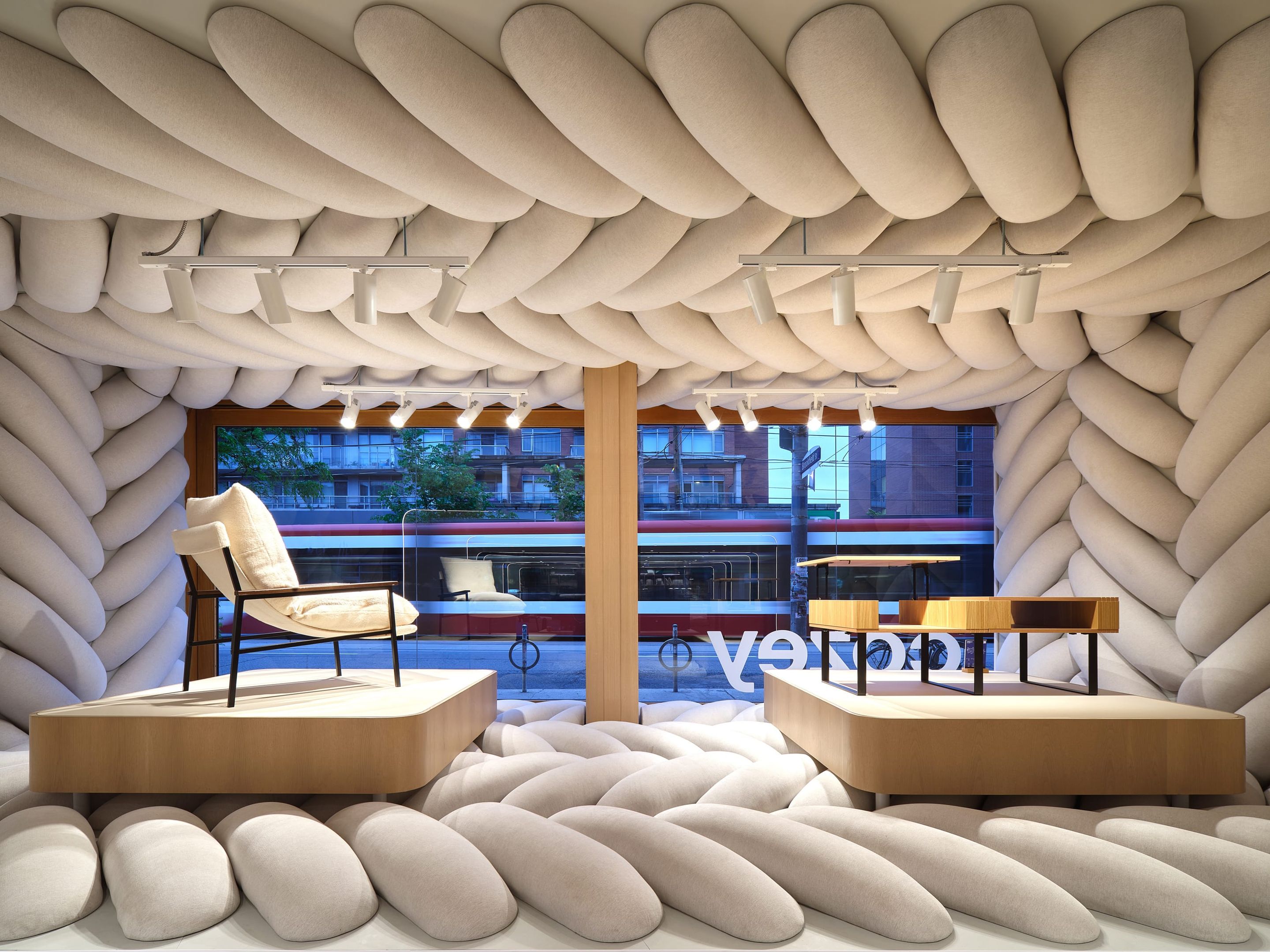 Vitrine immersive de la boutique phare Cozey à Toronto conçue par LAAB architecture avec murs capitonnés monumentaux et mobilier sur podium