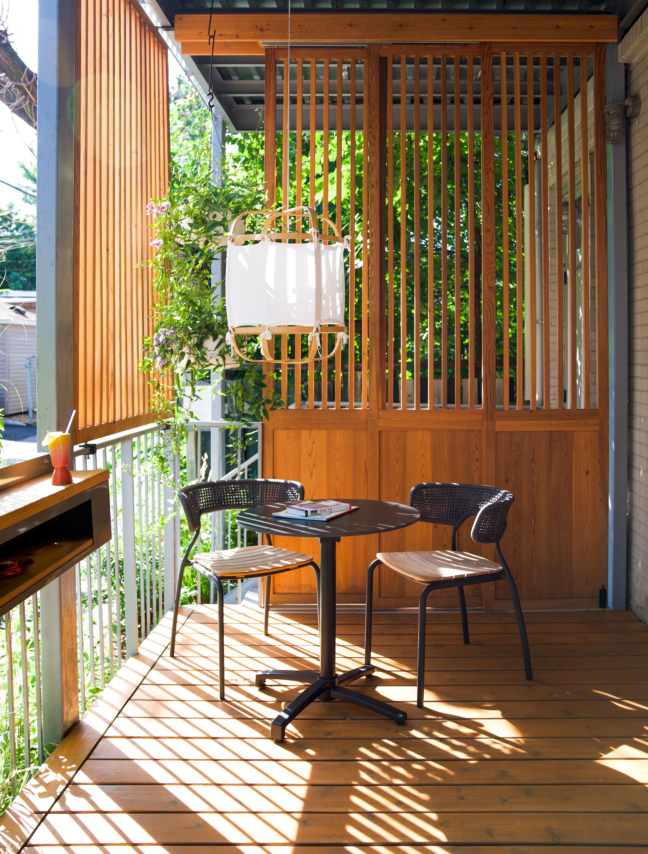 Loggia conçue par MYTO avec écran de bois ajouré, mobilier extérieur et végétation intégrée sur une terrasse urbaine.