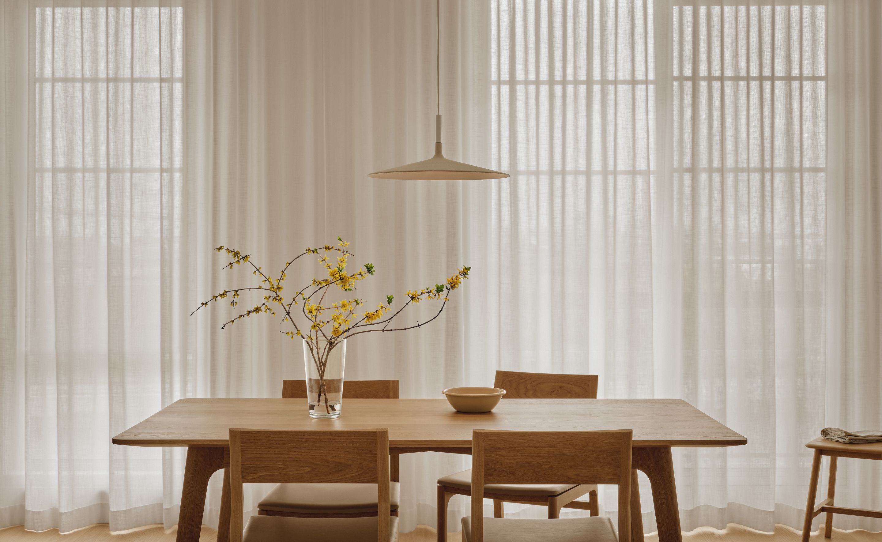 Salle à manger du projet St-Henri par Vives St-Laurent, table en bois massif et rideaux pleine hauteur diffusant la lumière naturelle.