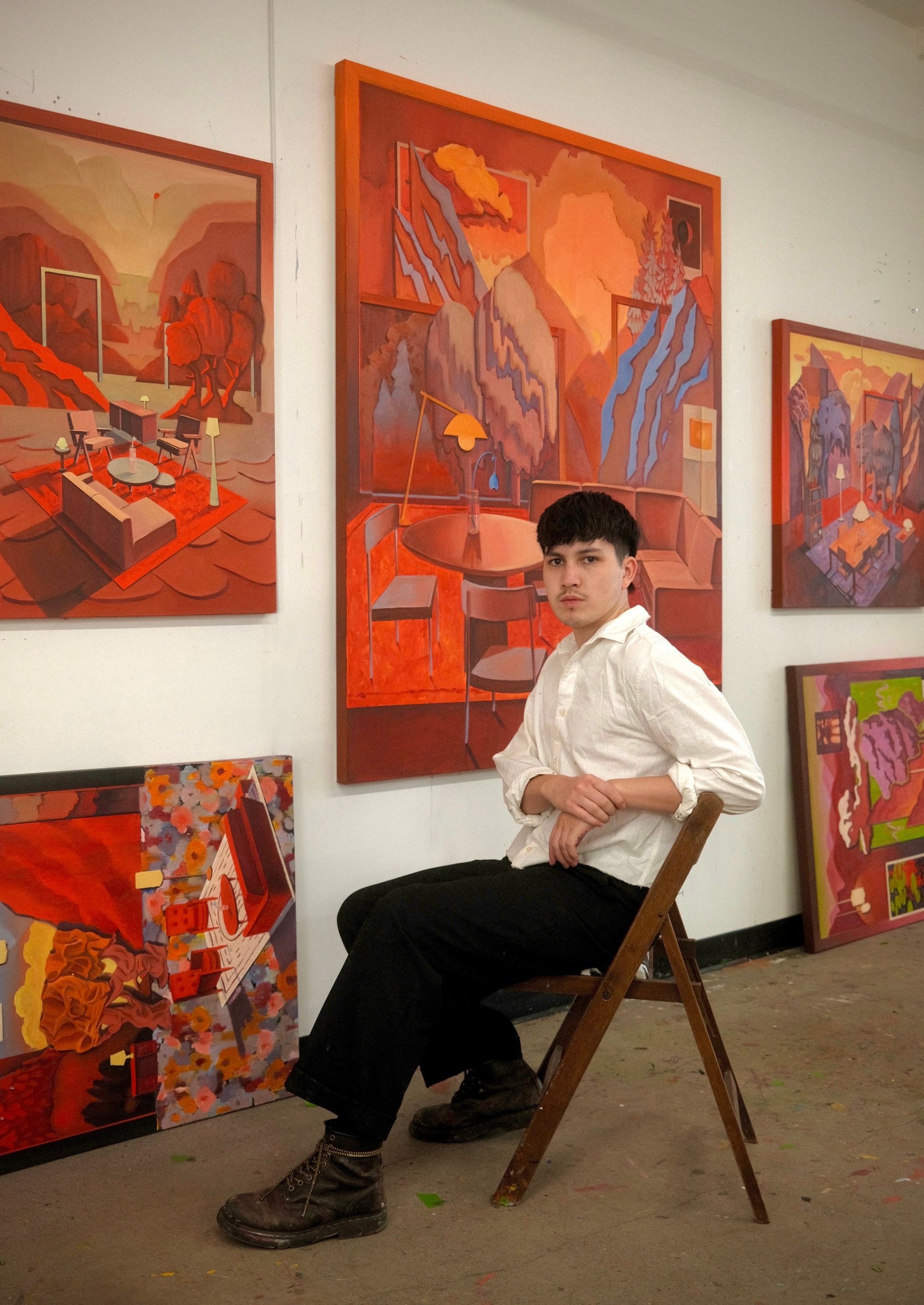 Charles Paradis dans son atelier entouré de ses peintures explorant les liens entre paysage, architecture et espace domestique.